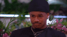 a man in a black hat is looking at a woman in a garden .