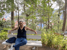 a man sits on a white bench in a park with trees in the background