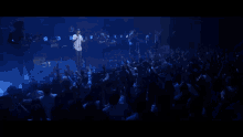 a man singing into a microphone with a crowd behind him