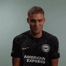 a man wearing a black american express shirt is smiling