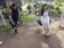 a man and a woman are swinging on tire swings in a park