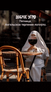 a nun sits at a table with a glass of wine