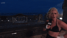 a woman in a bikini is holding a microphone that says aew on it