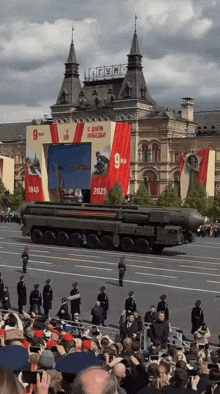 a crowd of people watching a military parade with a banner that says 9