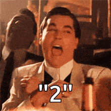 a man in a suit and tie is holding a glass with the number 2 written on it .