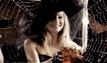 a woman wearing a witch hat is holding a glass of orange juice .