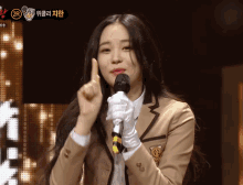 a girl in a school uniform is holding a microphone and giving a thumbs up
