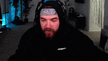 a man with a beard wearing a bandana and a hoodie with the word originals on the back .