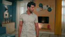 a man in a white shirt is standing in front of a television in a living room