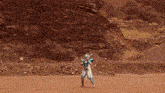 a person in a superhero costume stands in a dirt field