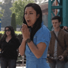 a woman in a blue jumpsuit with a watch on her wrist is praying