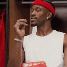 a man wearing a red headband eating a cheez-it snack