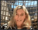 a woman with blonde hair is smiling in front of a cage