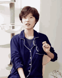 a woman in a blue shirt is sitting in a chair holding a pair of glasses