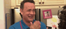 a man in a blue shirt is crying while standing in front of a refrigerator in a kitchen .