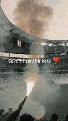 a stadium with smoke coming out of the stands and the words sevdim seni bir kere
