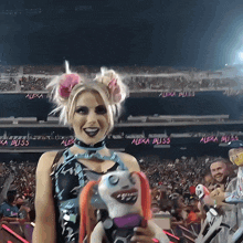 a woman holding a stuffed animal in front of a sign that says alexa bliss on it