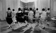 a group of women are dancing in a room in front of a man playing a trumpet .