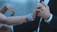 a man in a suit and tie is putting a wedding ring on a woman 's finger .