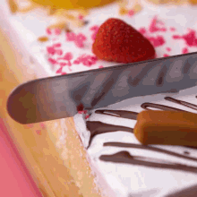 a knife is being used to cut a cake with strawberries on top