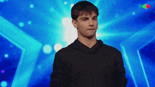 a young man in a black hoodie is standing on a stage