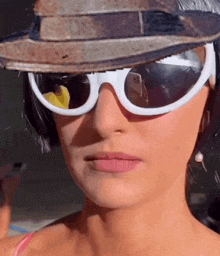 a woman wearing sunglasses and a hat with a reflection of a person