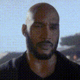 a bald man with a beard is looking at the camera