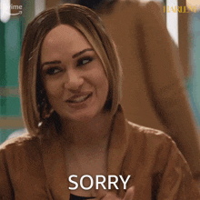 a woman in a brown jacket is making a sorry face