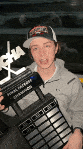 a man holding a trophy that says final faceoff champion on it