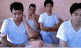 a group of men in white shirts are sitting on a bed with their arms crossed ..