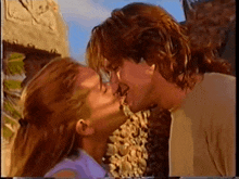 a man and a woman are kissing in front of a rock wall
