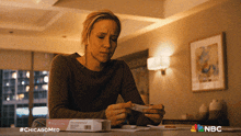 a woman sitting at a table with a box of pills and a nbc logo on the bottom
