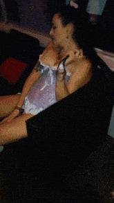 a woman sits on a couch with her legs crossed and a necklace around her neck
