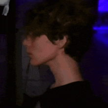 a close up of a young man 's face in a dark room with a blue light behind him .