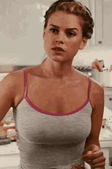 a woman in a striped tank top is holding a cup