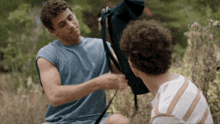 a man in a blue shirt is talking to another man in a white striped shirt