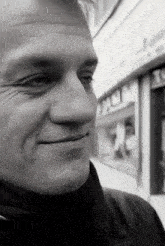 a man is smiling in front of a building that says tc