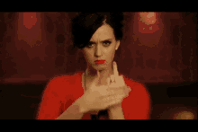 a woman in a red dress is making a rude gesture with her hands .
