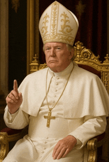 a man wearing a white robe and a gold cross necklace is sitting in a chair