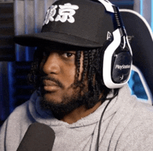 a man wearing a playstation headset and a tokyo hat