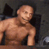 a shirtless man with a smiley face on his face is sitting in front of a mirror .