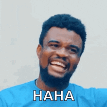 a man with a beard and a blue shirt is laughing with the words `` haha '' written on his face .