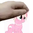 a pink pony is standing next to a hand holding a donut .