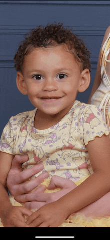 a little girl wearing a winnie the pooh shirt smiles