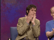 a man in a suit is laughing and covering his mouth with his hand