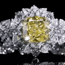 a close up of a diamond ring with a yellow diamond in the center .