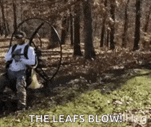 a man is using a parachute to blow leaves in a forest .