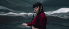 a woman in a red jacket stands in a dark room