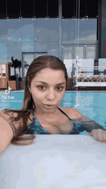 a woman in a bikini is taking a selfie in a pool with tiktok written on the bottom right