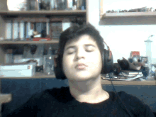 a young man wearing headphones with his eyes closed in front of a bookshelf